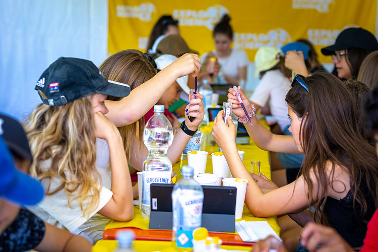 Kinder und Jugendliche experimentieren konzentriert mit Reagenzgläsern an einem langen Tisch bei einem naturwissenschaftlichen Mitmachangebot von Explore Science.